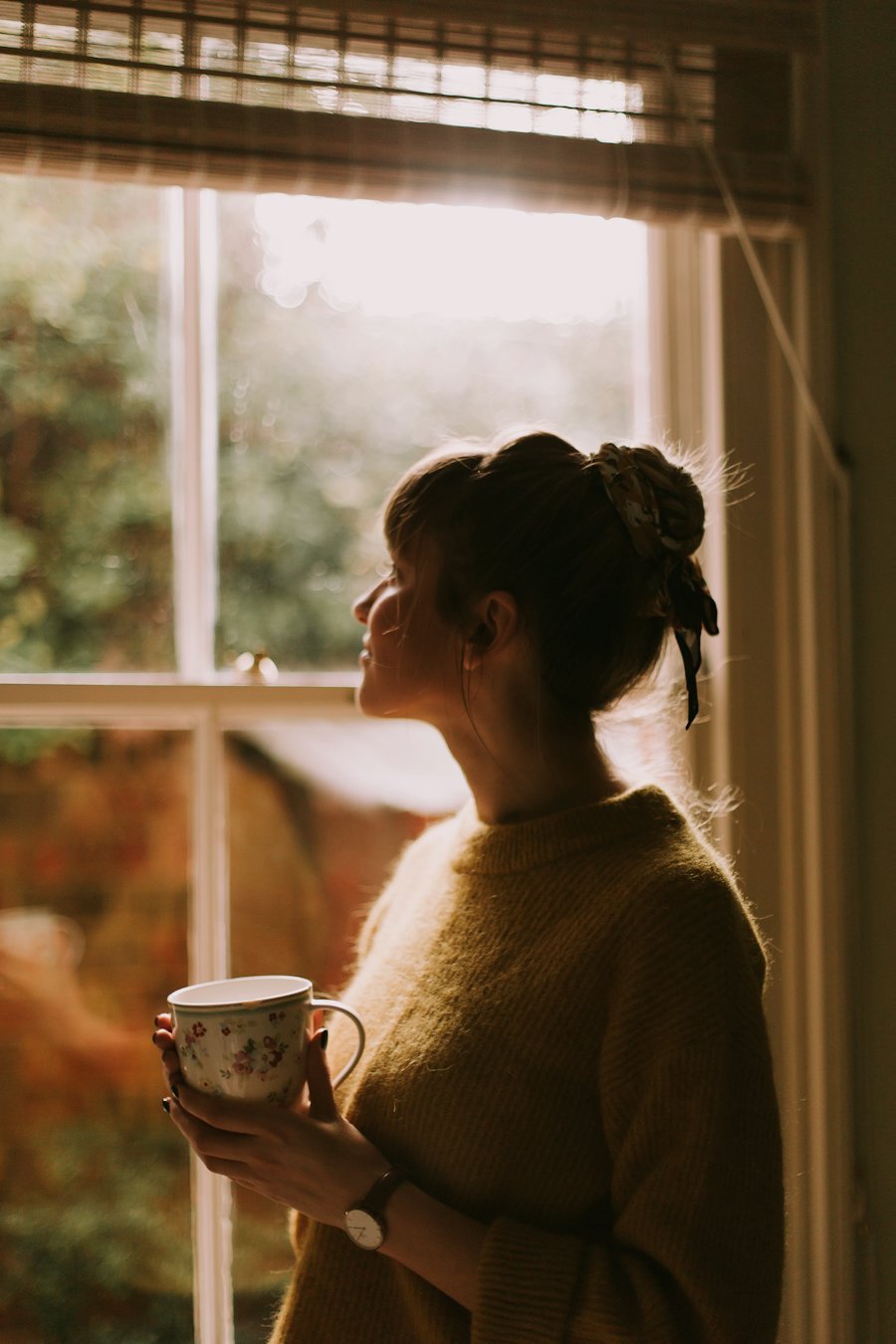 Une femme pensive près d'une fenêtre