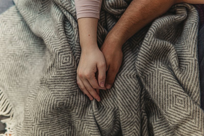 Les mains d'un couple posées sur une couverture