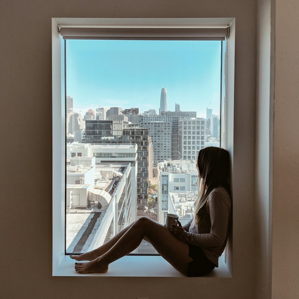 Une femme assise sur le rebord d'une fenêtre